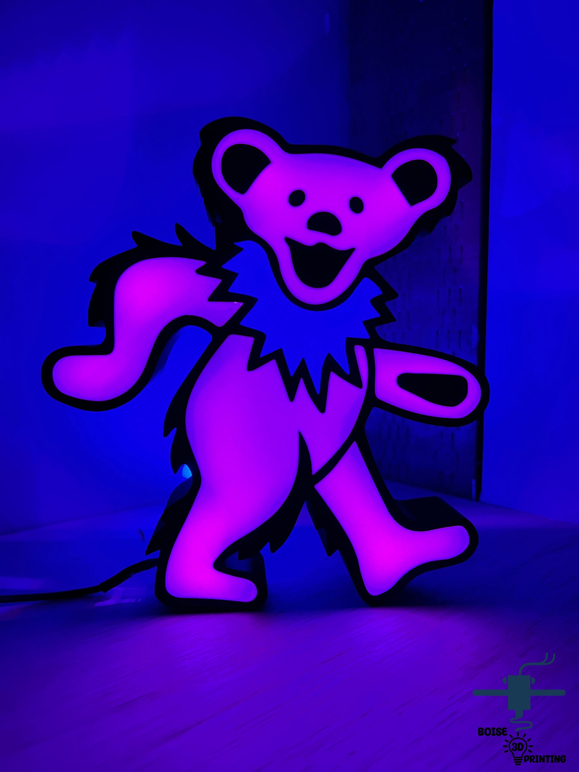 a purple teddy bear sitting on a wooden floor